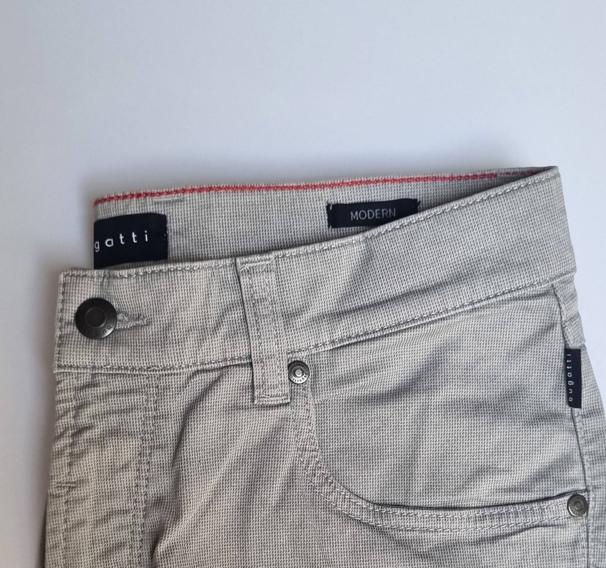 Close-up of gray pants with brand labels on a white background