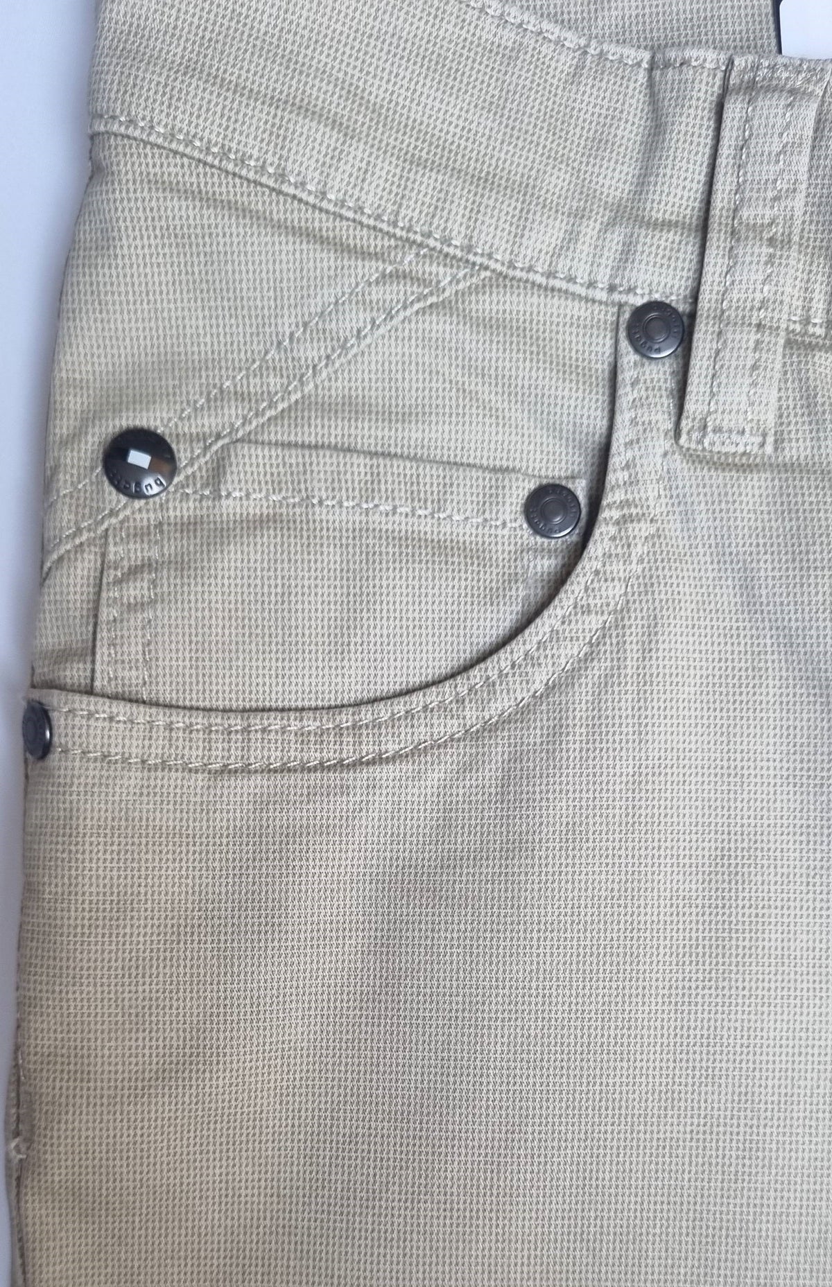 Close-up of beige pants with button details on a white background