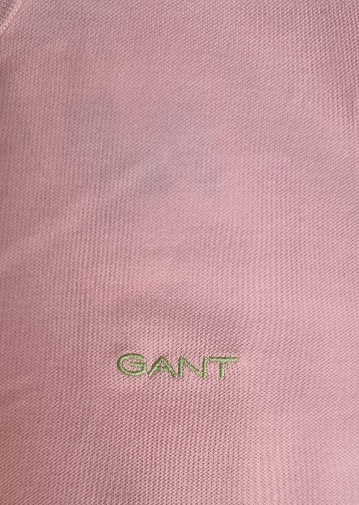 Close-up of a pink fabric with &#39;GANT&#39; logo embroidered on it.