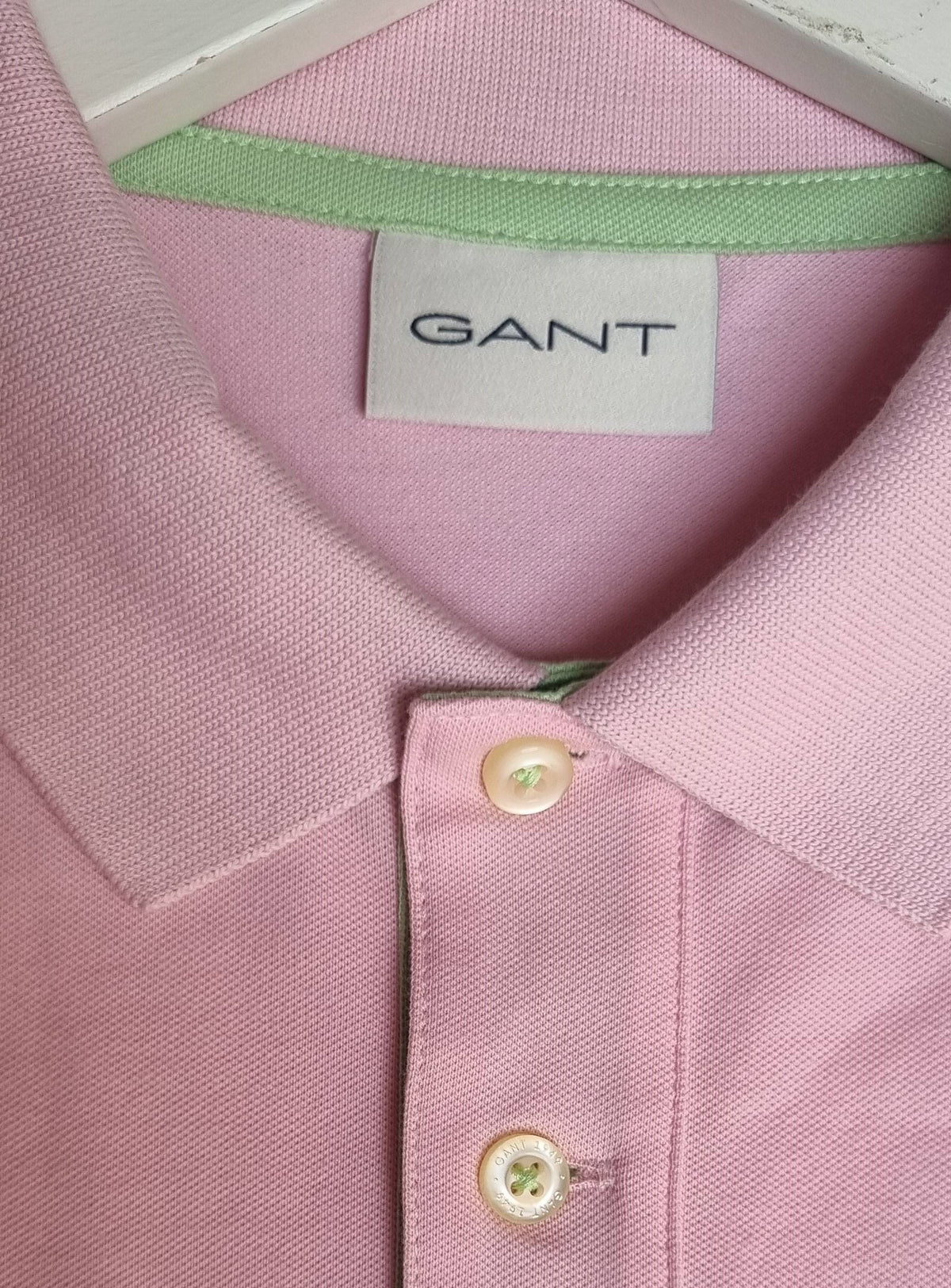 Close-up of a pink Gant shirt with a tag showing the brand name.