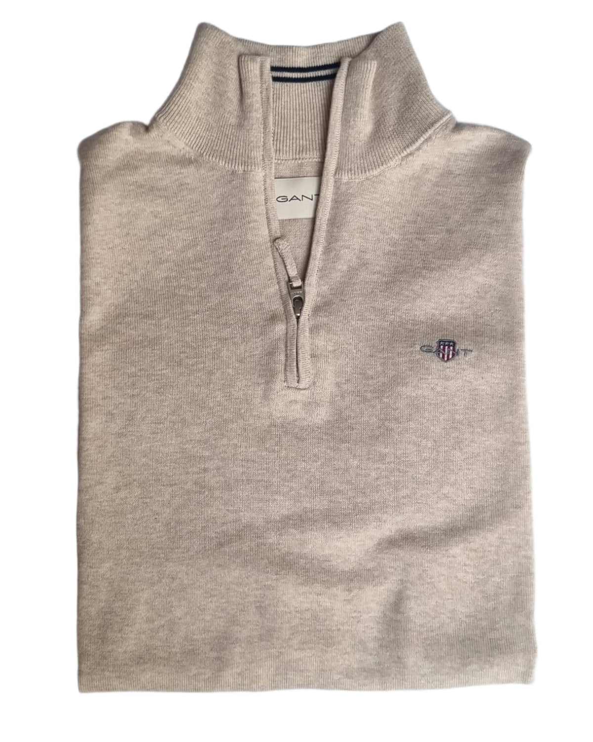 Folded beige sweater with Gant logo on a light gray background