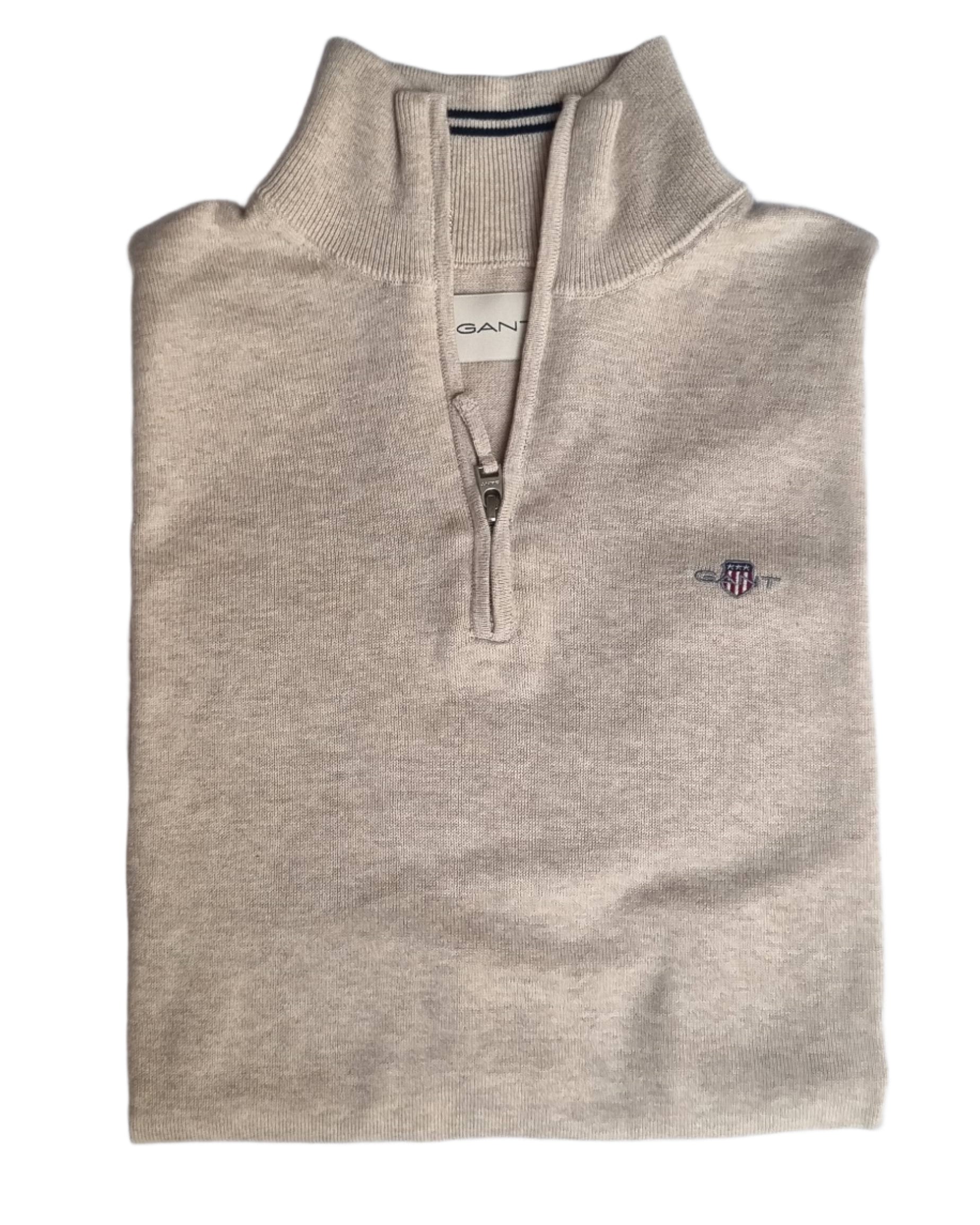 Folded beige sweater with Gant logo on a light gray background