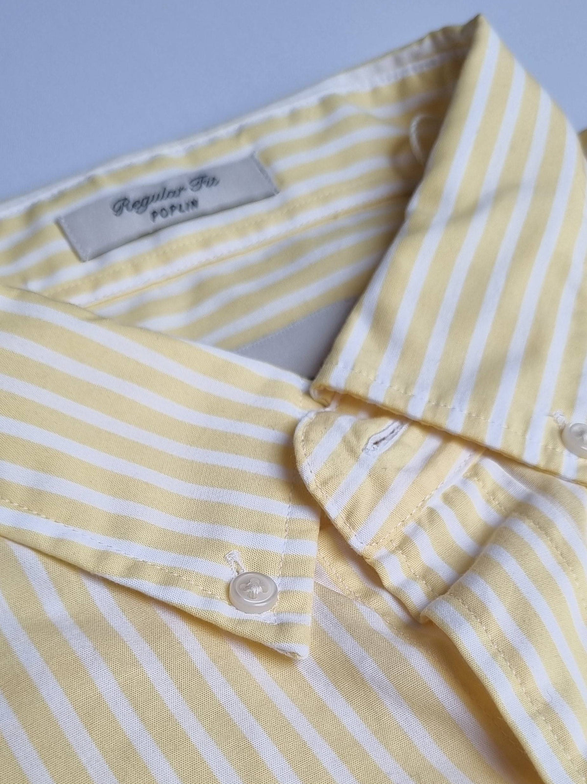 Yellow and white striped shirt with a &#39;Regular Fit&#39; label on a light blue background