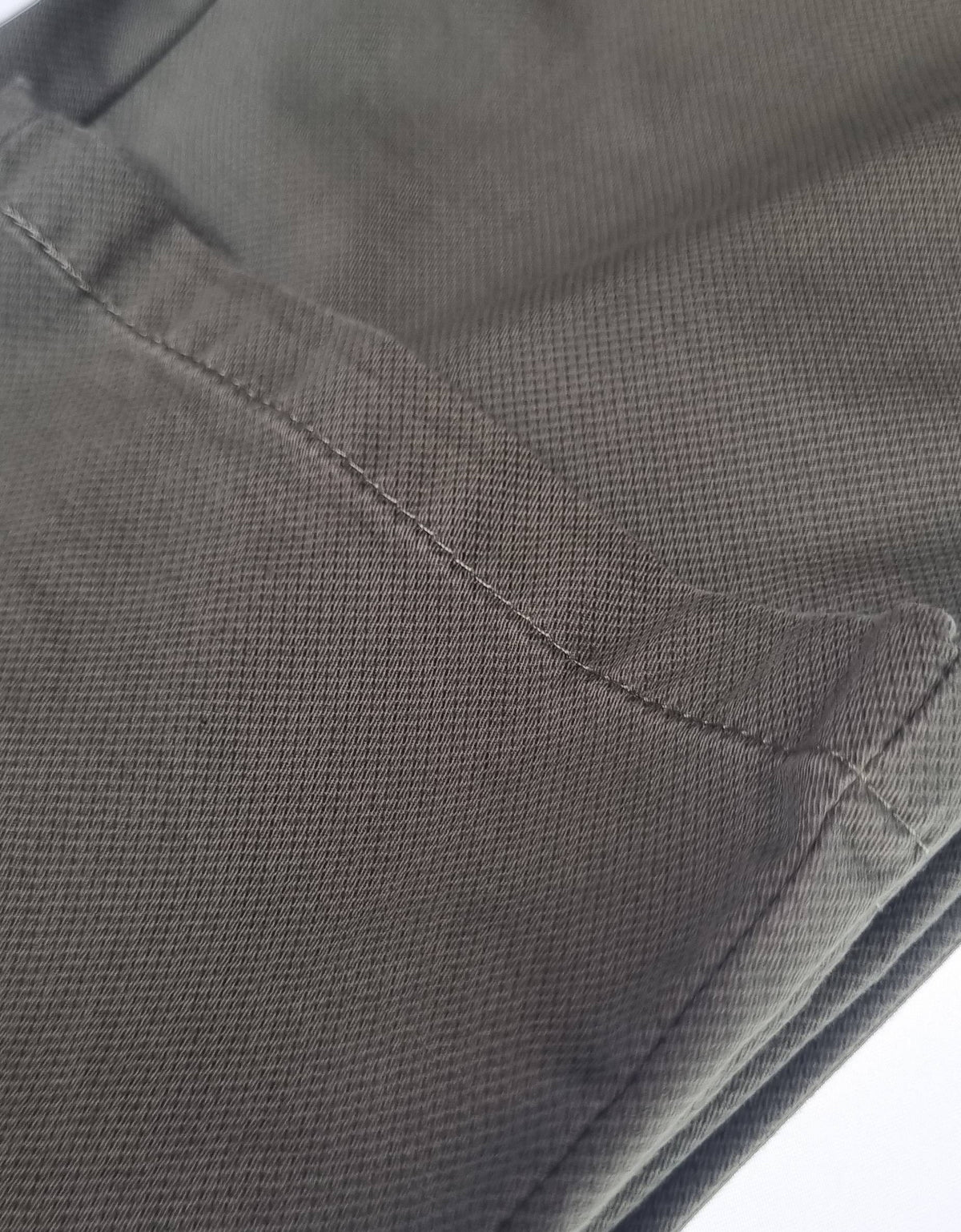 Close-up of dark gray pants with a visible seam on a white background