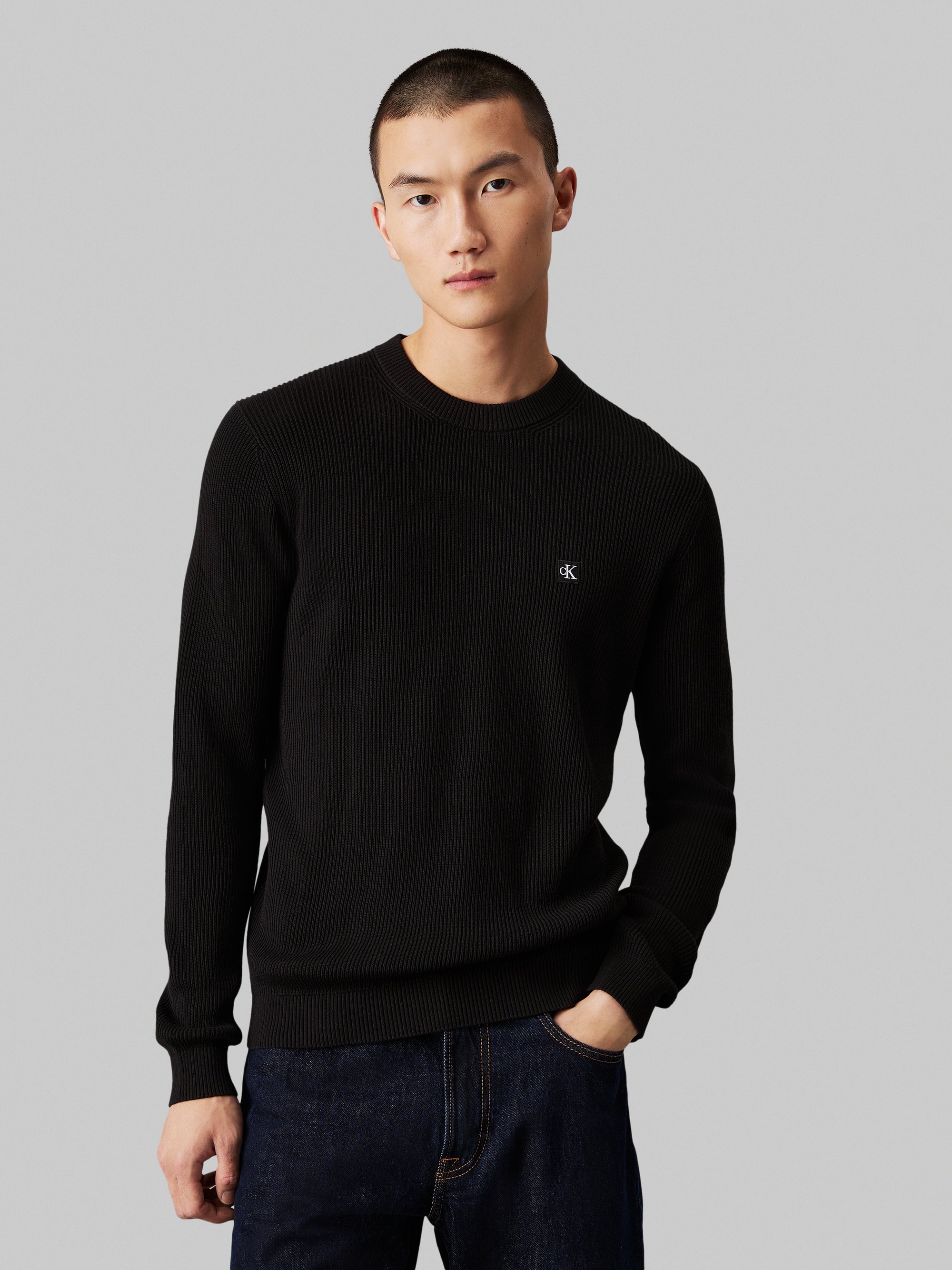 Calvin Klein Embro Badge Sweater. Featuring a soft knit fabric and iconic embroidered badge, this versatile crew neck jumper combines comfort with minimalist style.