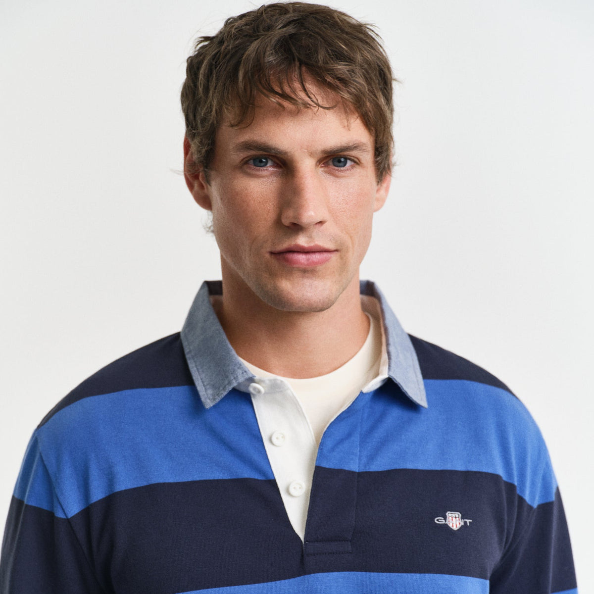 Man wearing a blue and navy striped polo shirt with a visible brand logo 